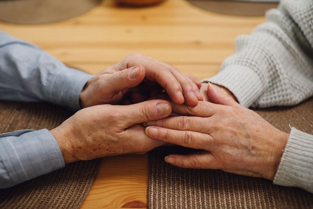 Two pairs of weathered hands joined across a table