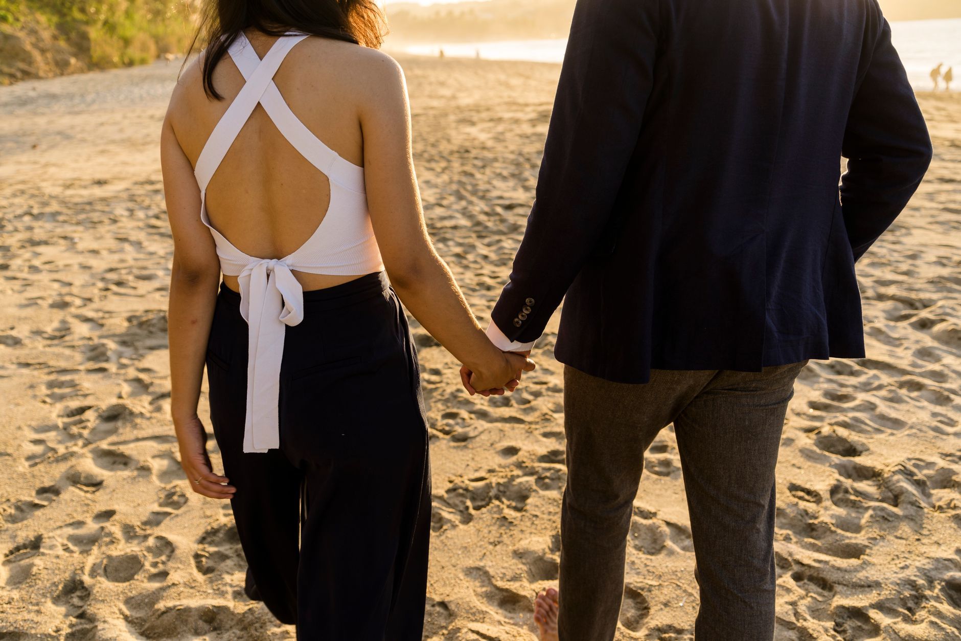 A couple holding hands walking on the beach at sunset