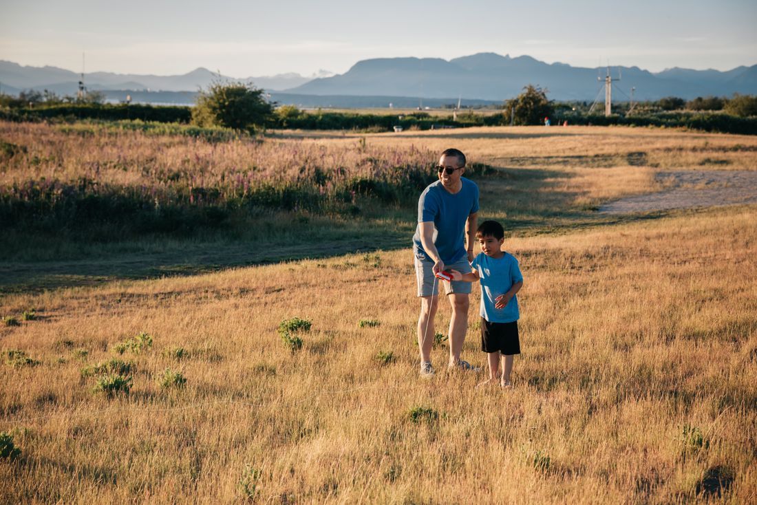 A father and son playing together in a field at sunset