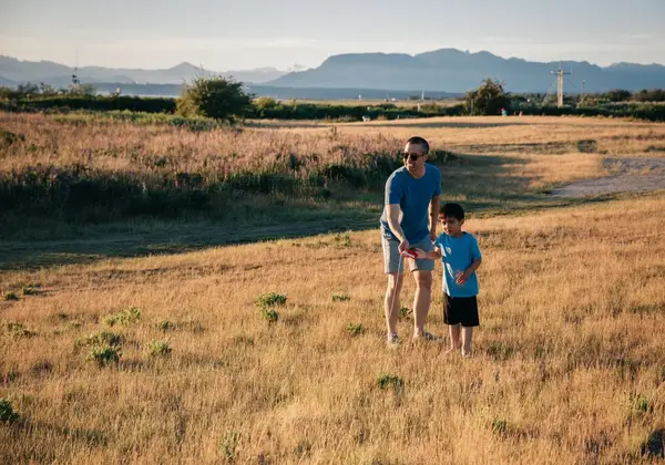 A father and son playing together in a field at sunset