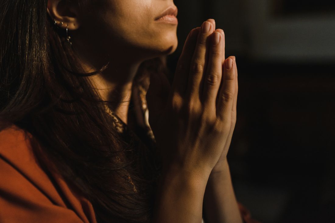A woman's hands clasped in quiet prayer