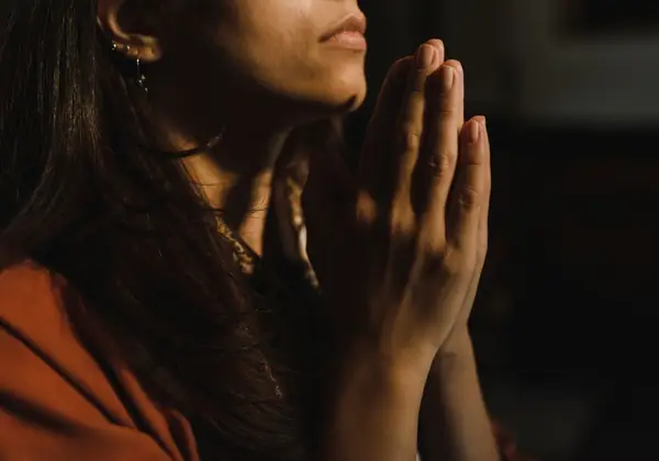 A woman's hands clasped in quiet prayer
