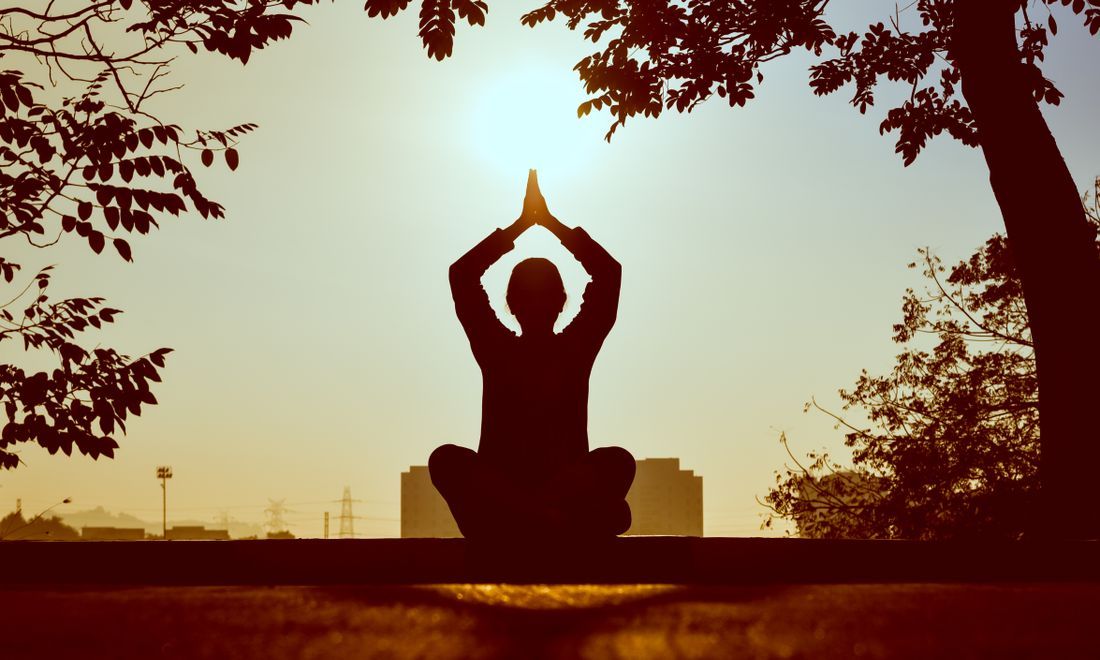 A silhouette in meditation as the sun rises