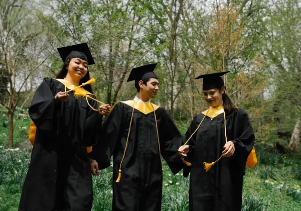 Three graduates smiling with their tassels