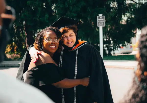 A graduate embracing a mentor with gratitude