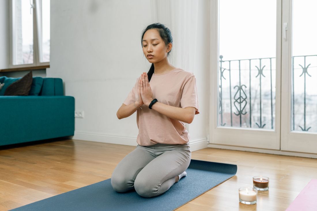 A woman meditating peacefully at home by a sunlit window