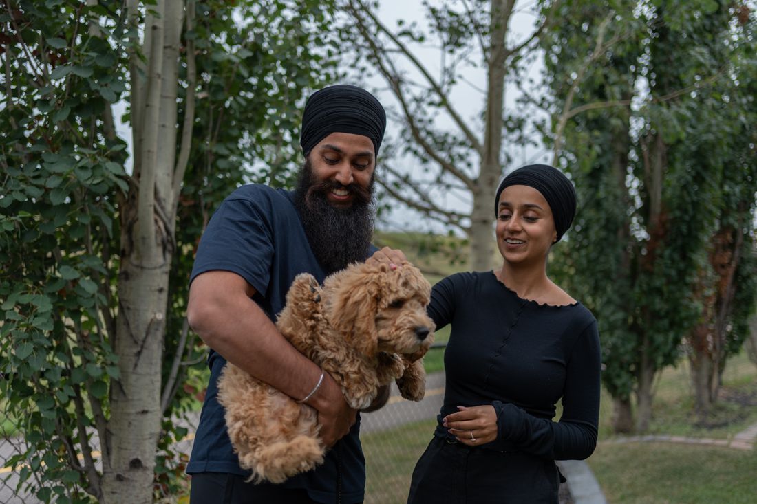 A young couple smiling together with their puppy