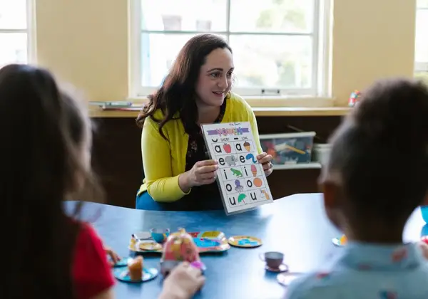 A children's ministry volunteer teaching young kids with a picture chart
