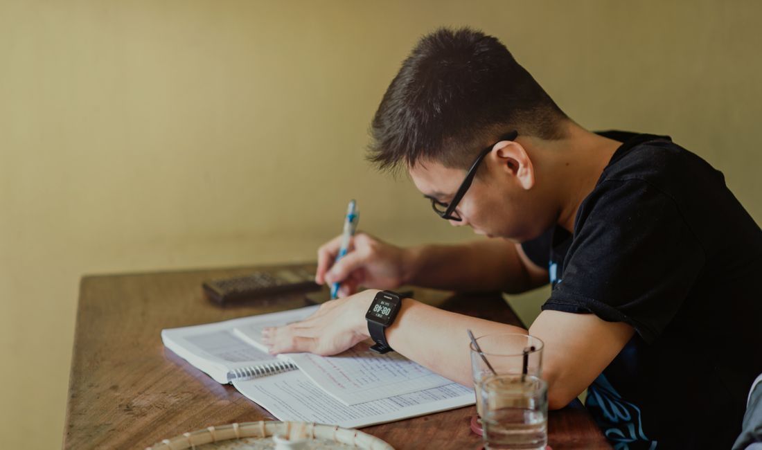 A student focused on his notes at a quiet table