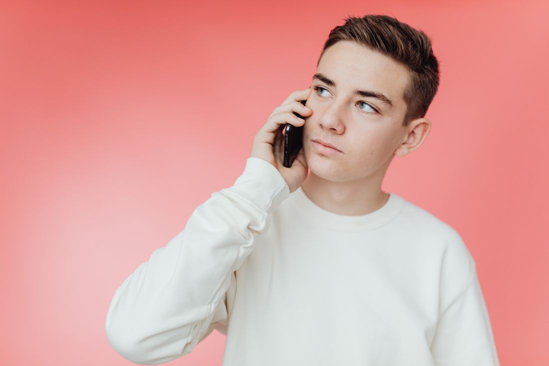 A teenage boy on the phone, looking away