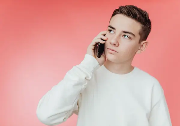 A teenage boy on the phone, looking away