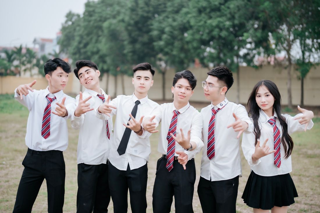 A group of high schoolers in uniform laughing together outdoors