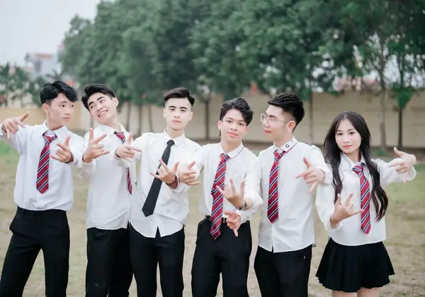 A group of high schoolers in uniform laughing together outdoors