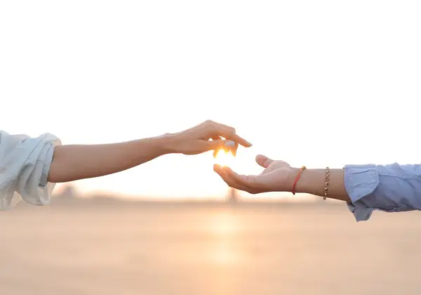 Two hands reaching toward each other with the sun between them