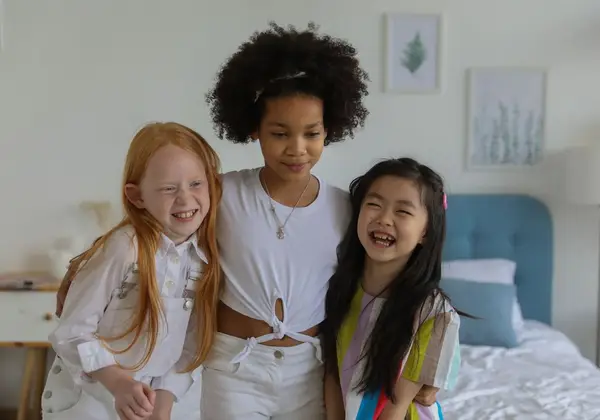 Three girls of different backgrounds hugging and smiling