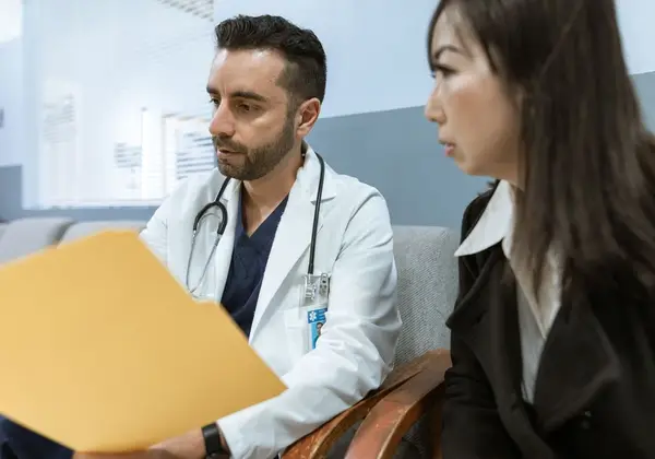 A doctor reviewing a patient's file with her in consultation