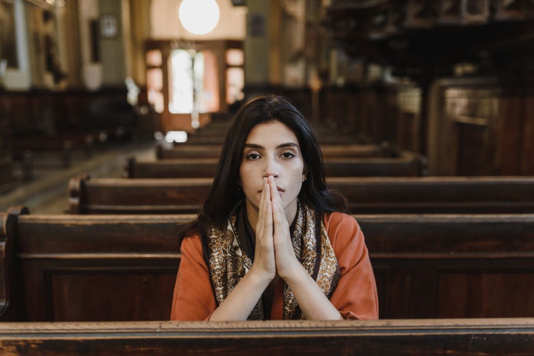 A woman praying quietly in the pews