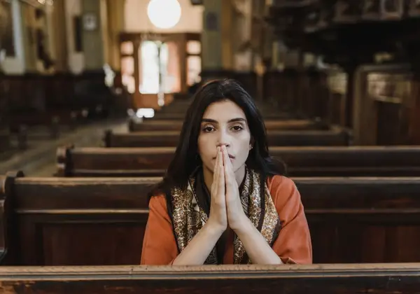 A woman praying quietly in the pews