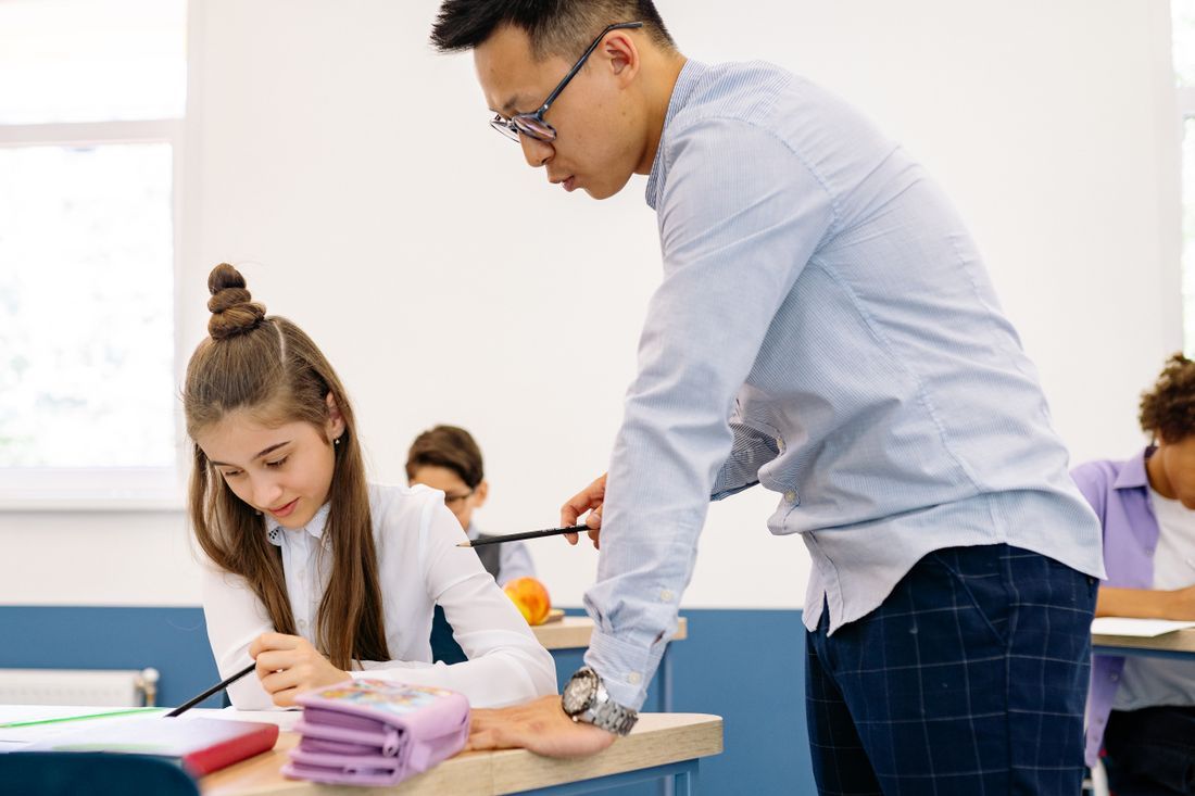 A teacher leaning in to help a student with her work