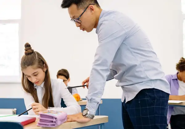 A teacher leaning in to help a student with her work