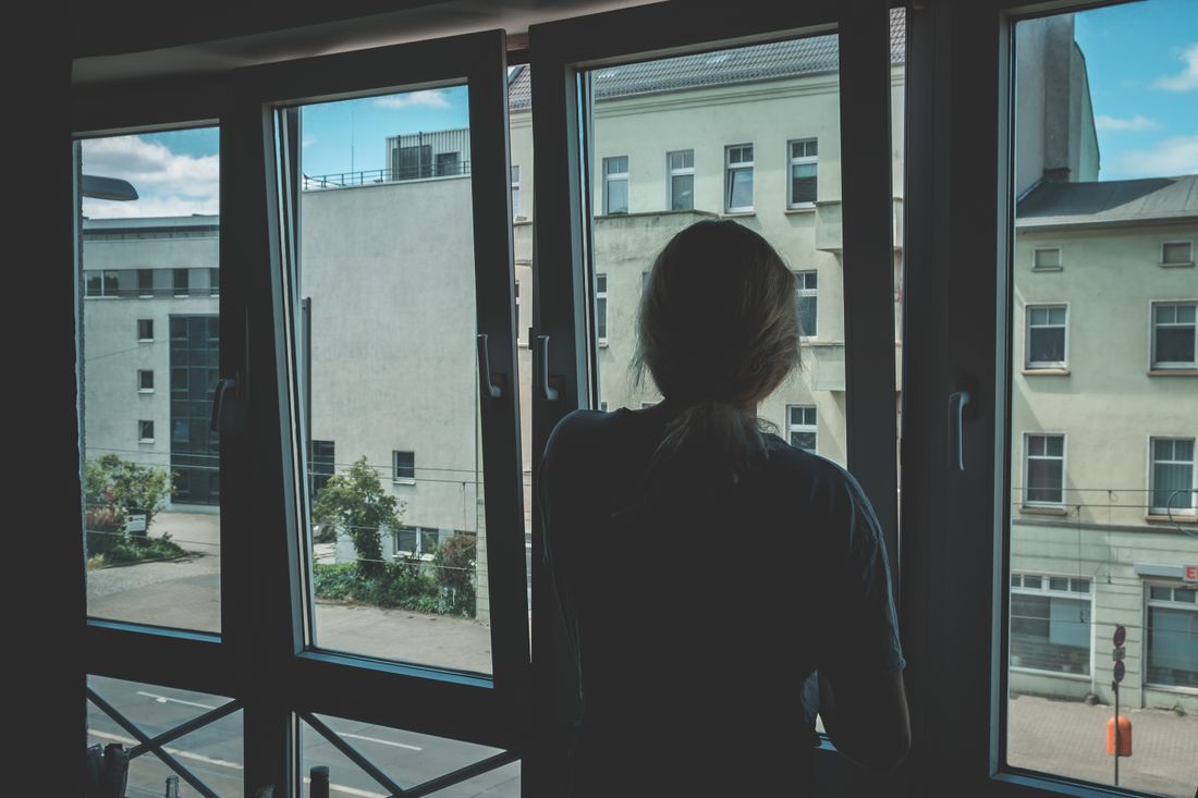 A woman looking out a window in a quiet, lonely moment