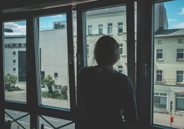 A woman looking out a window in a quiet, lonely moment