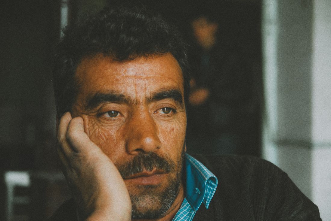 An older man resting his head on his hand, pensive