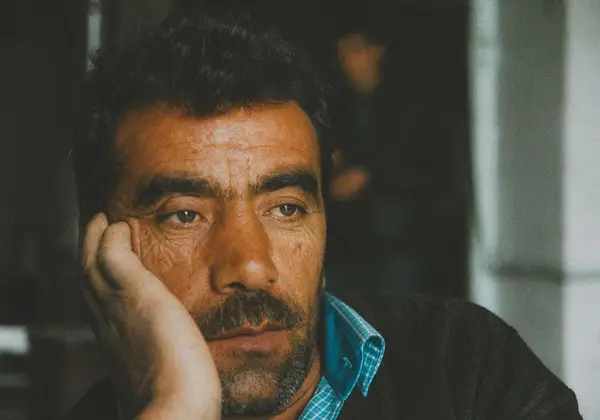 An older man resting his head on his hand, pensive