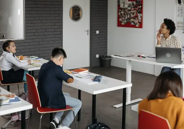 A teacher at her desk while students work quietly