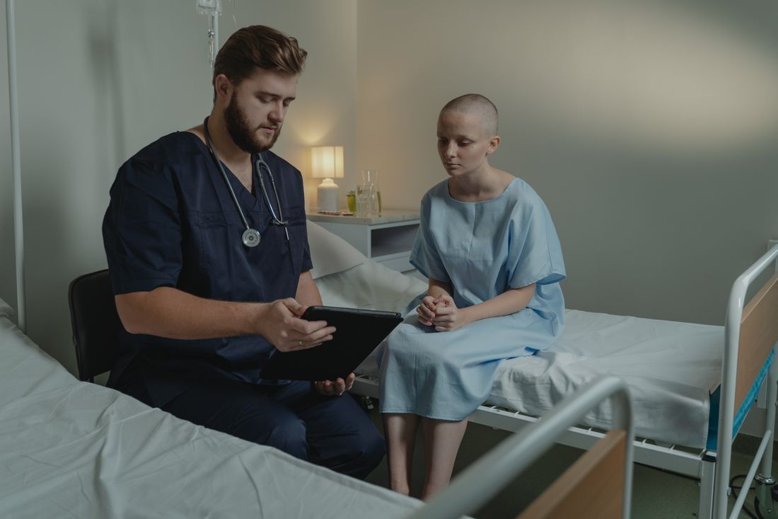 A nurse's hand resting over a patient's hand in comfort