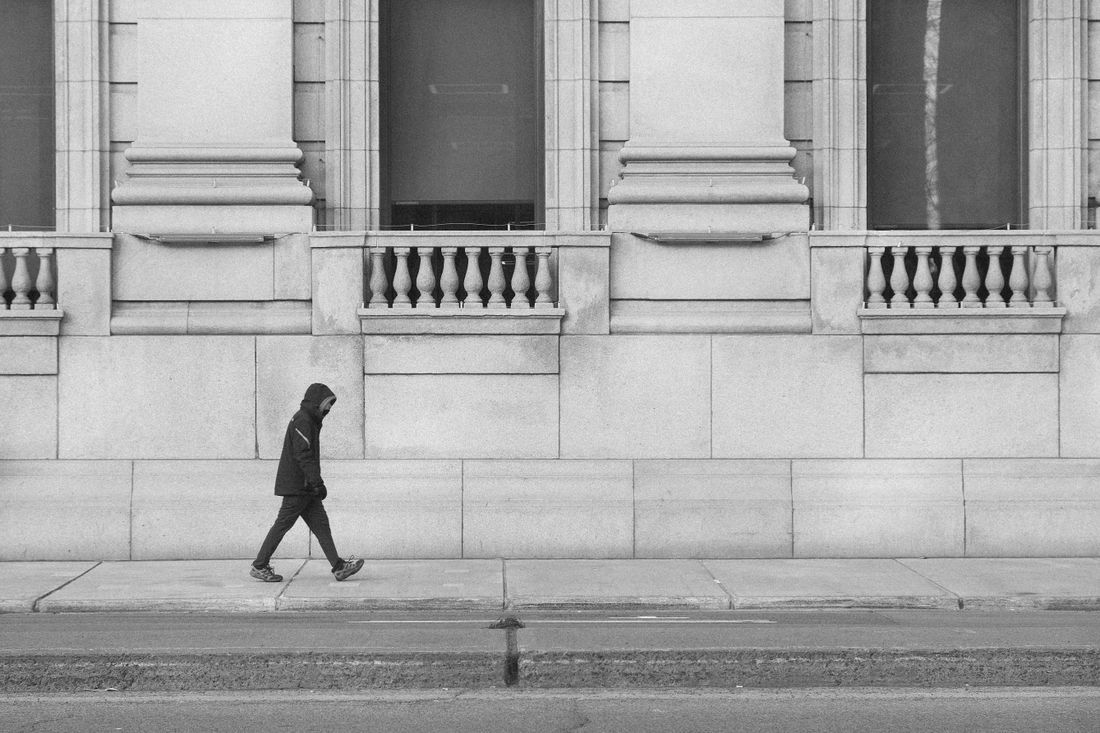 A lone figure walking past a grand stone building
