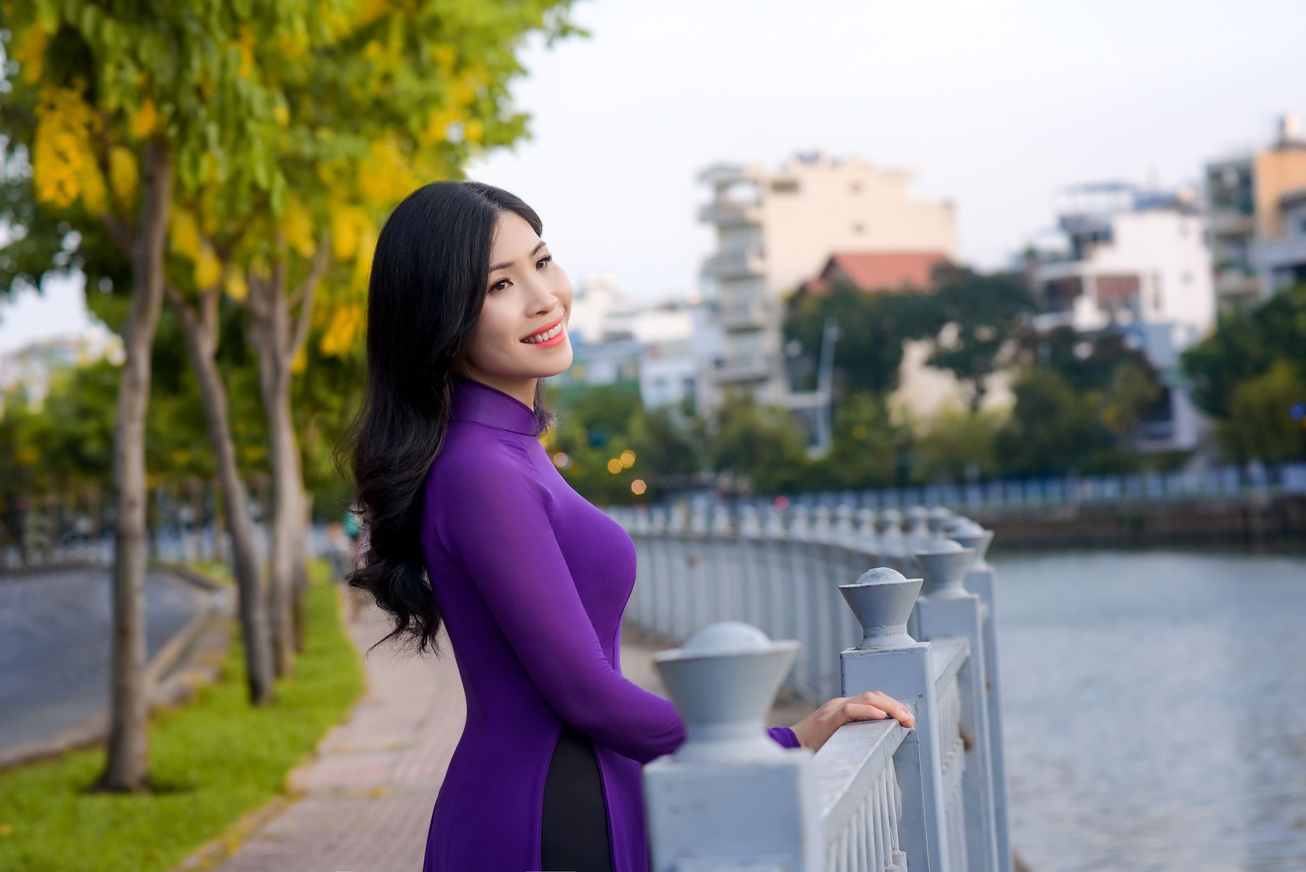 A Vietnamese woman in a purple ao dai by the river