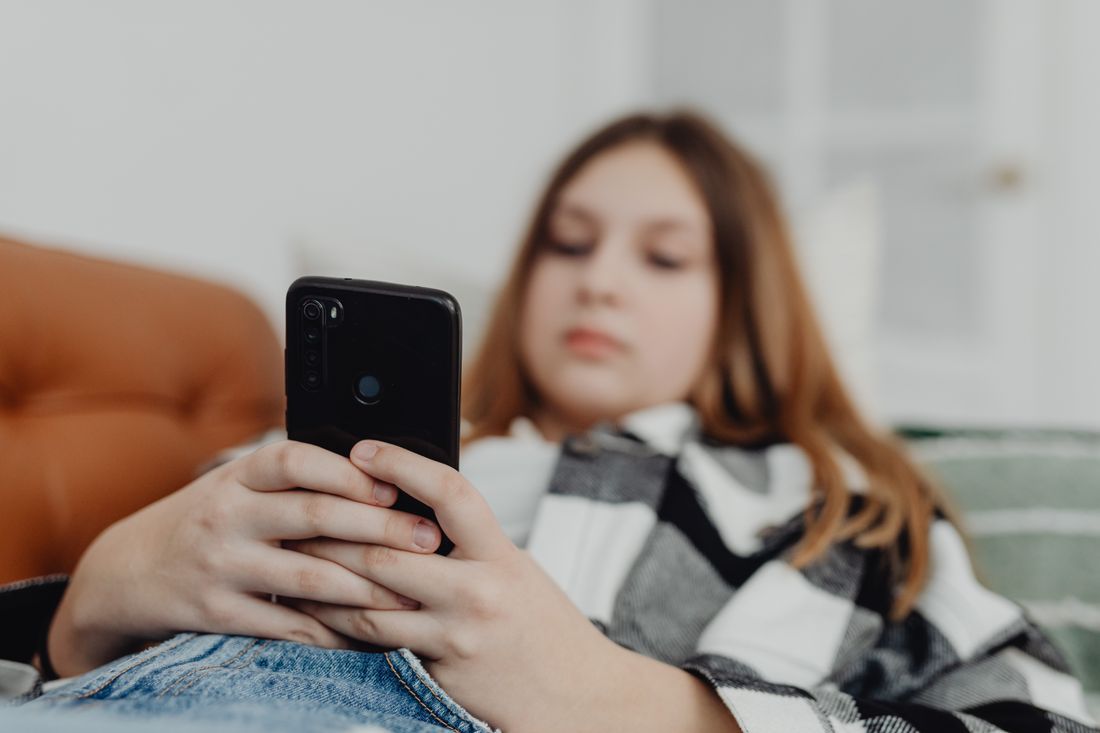 A teenage girl lying down, absorbed in her phone