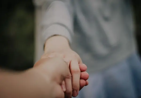 One person gently holding another's hand