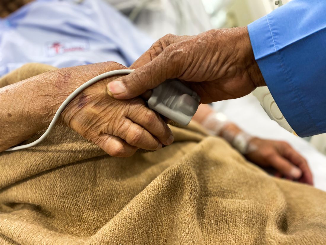 A caregiver tending to an elderly patient's hand