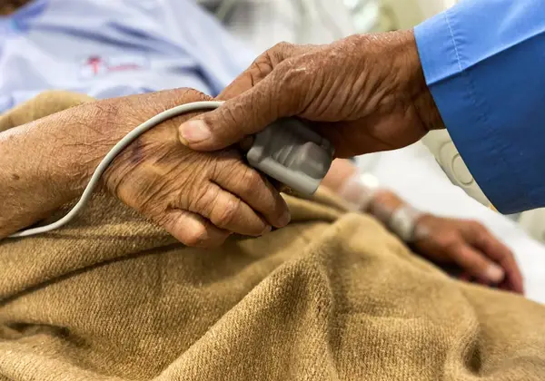 A caregiver tending to an elderly patient's hand