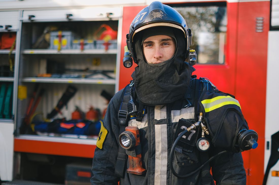 A firefighter in full turnout gear beside the truck