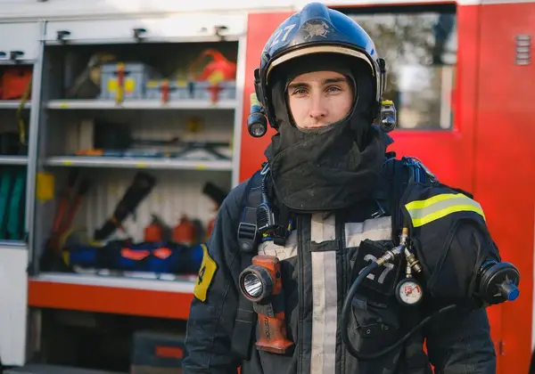 A firefighter in full turnout gear beside the truck