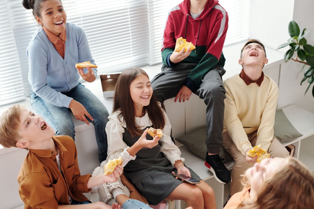 A group of tweens laughing and sharing pizza together