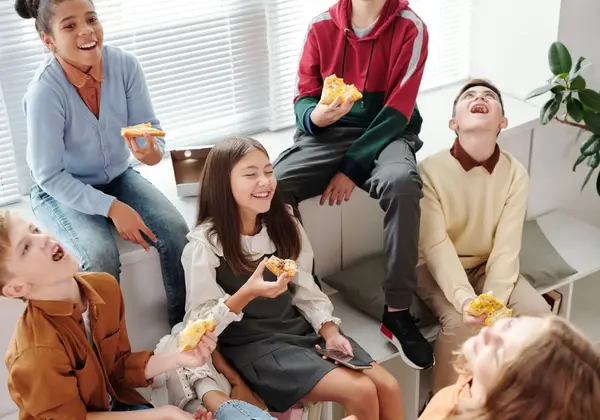 A group of tweens laughing and sharing pizza together