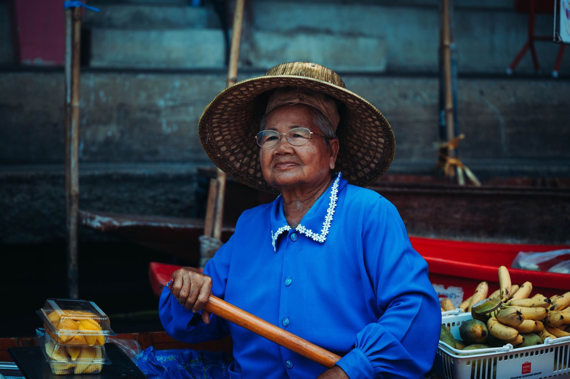 An elderly Thai woman selling fruit at a floating market