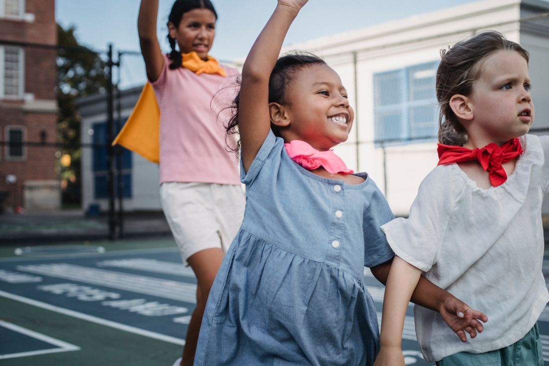 Children outdoors with arms raised in joy