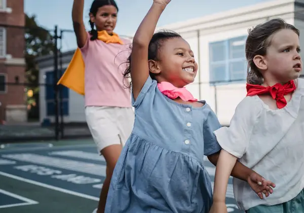 Children outdoors with arms raised in joy