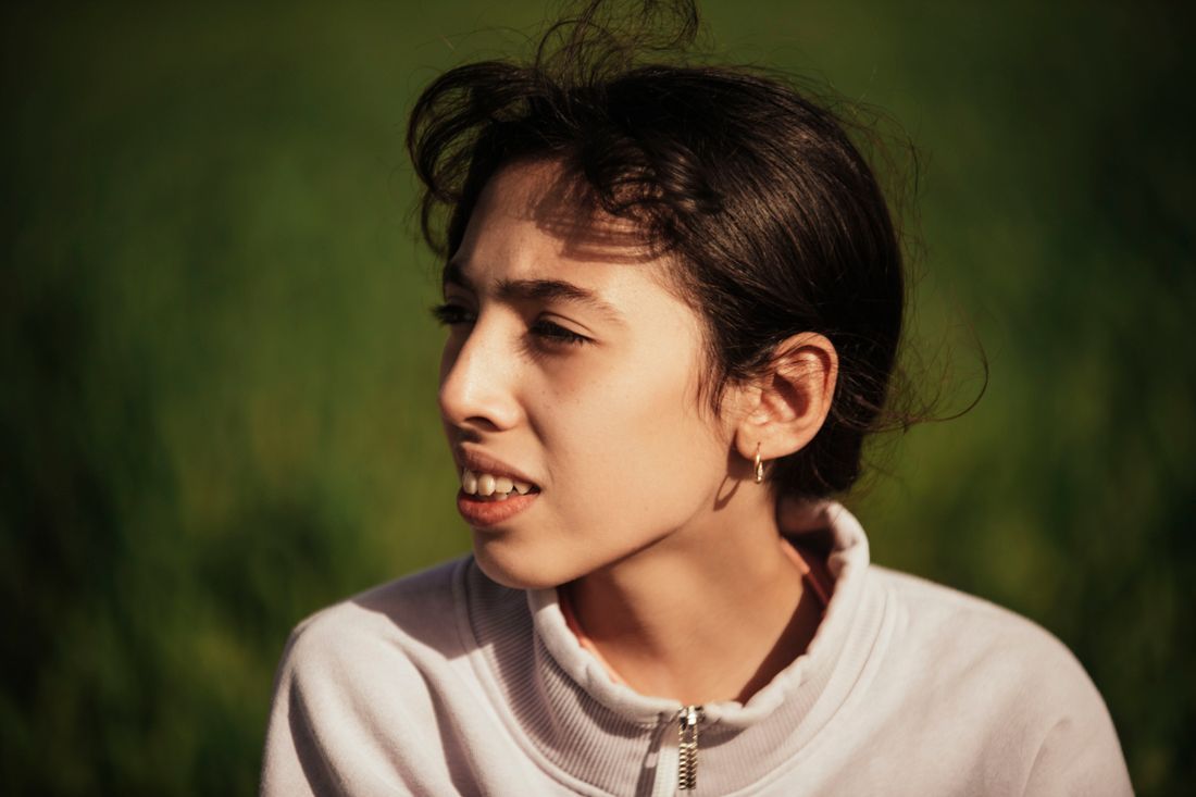 A young woman outdoors, thinking honestly