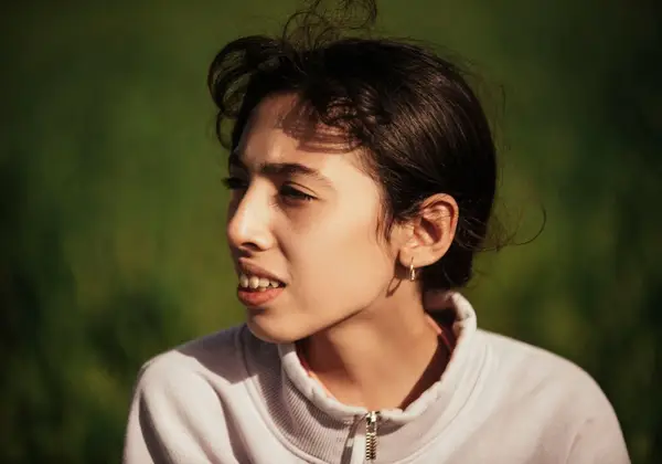 A young woman outdoors, thinking honestly