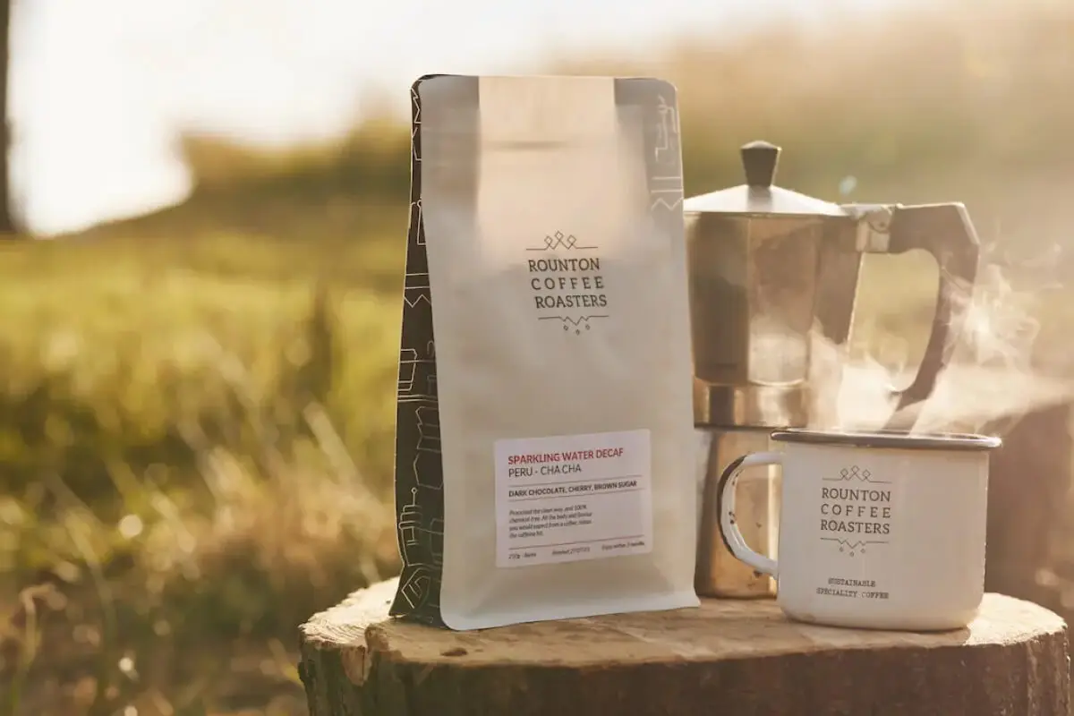 A bag of Rounton Coffee and a Cup on a tree stump with Rounton Coffee Branding