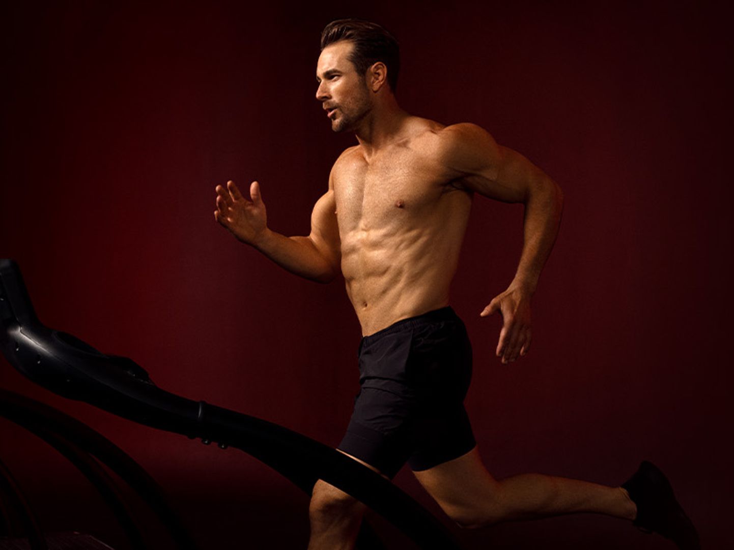 en man utan skjorta springer på ett löpband.