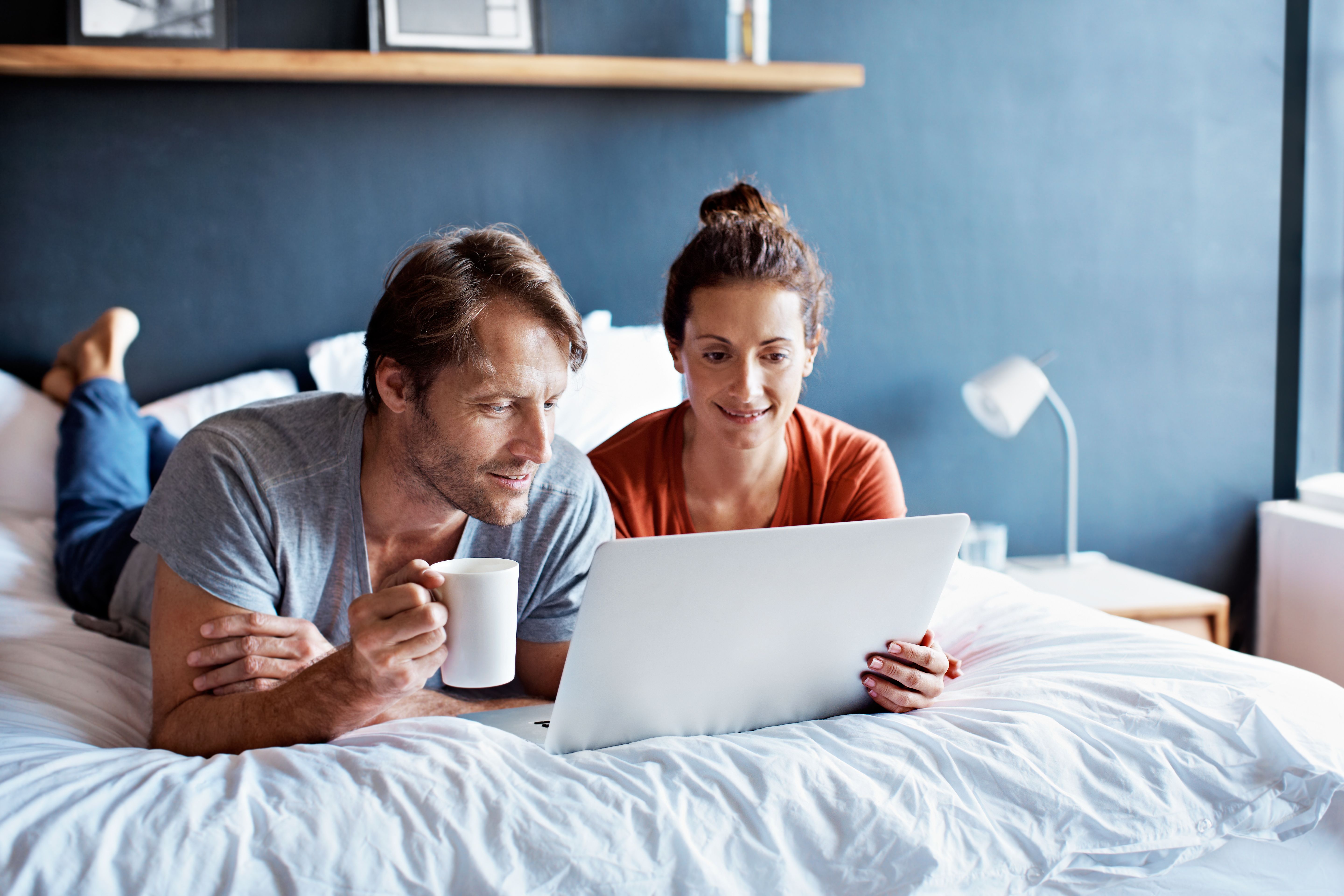Couple looking at a laptop together while relaxing at home.