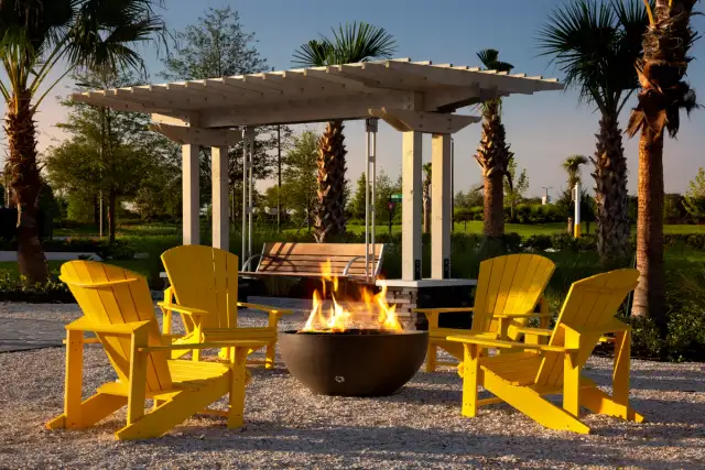 Outdoor firepit seating area at North River Ranch with Adirondack chairs, pergola, and landscaped gathering space for residents to relax and socialize.