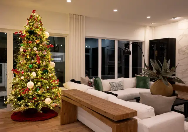 Christmas tree inside a Cardel Homes Alpine Park Calgary showhome, decorated for TreeFest beside a living room seating area.